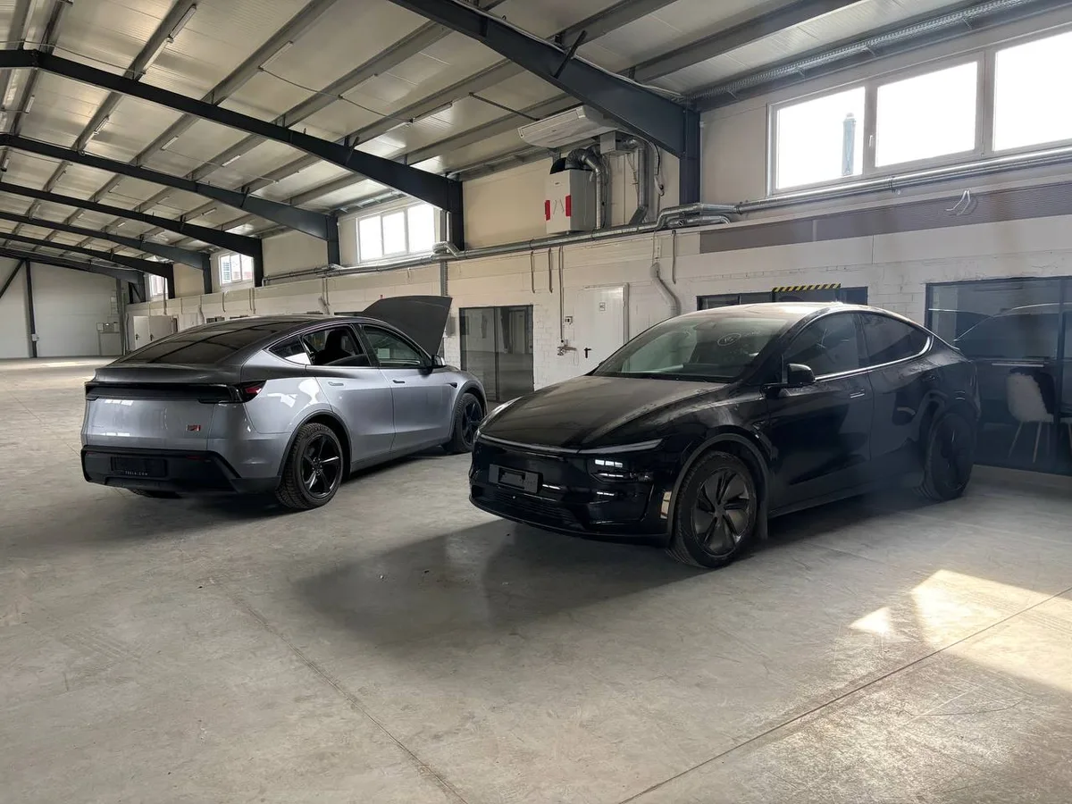 Two Tesla Model Y Juniper vehicles in the RR Car Parts workshop — silver and black, ready for suspension inspection