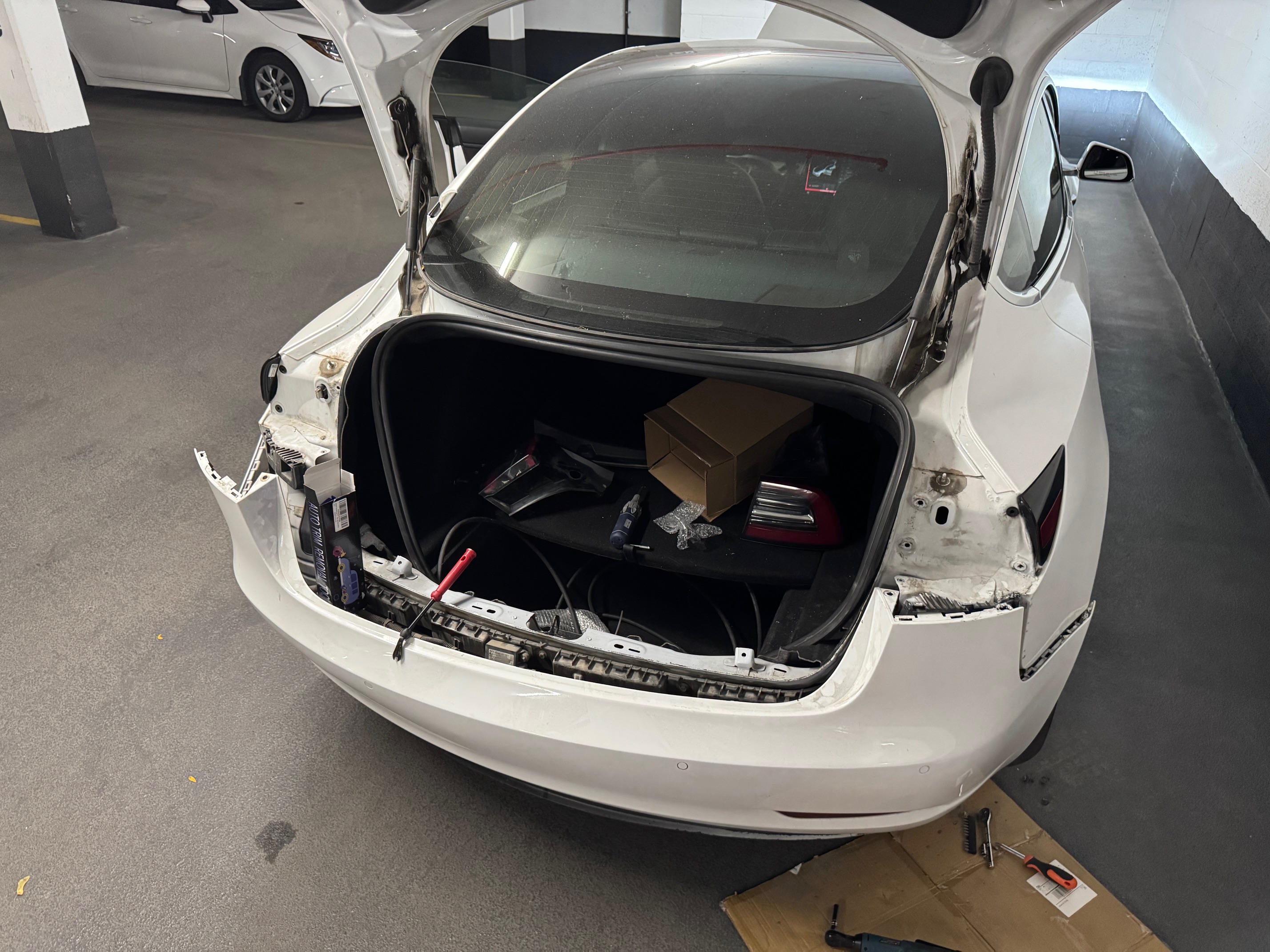 Reader's Model 3 with rear lights removed and rear fascia released and pulled away, exposing the rear access area